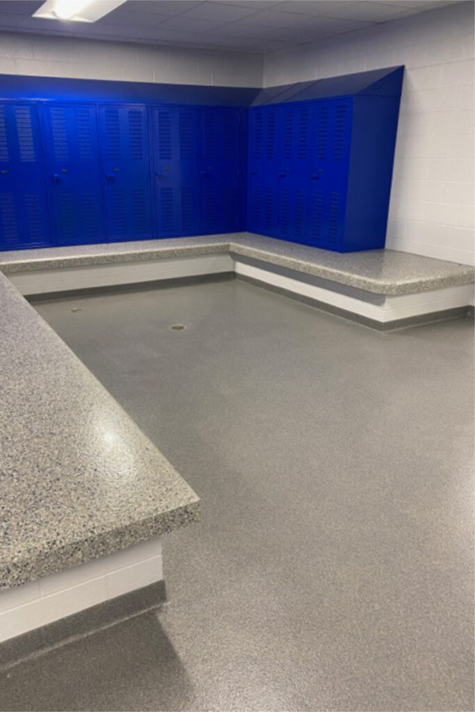 Locker room with blue lockers that have a slanted top; integral benches that have a decorative epoxy chip