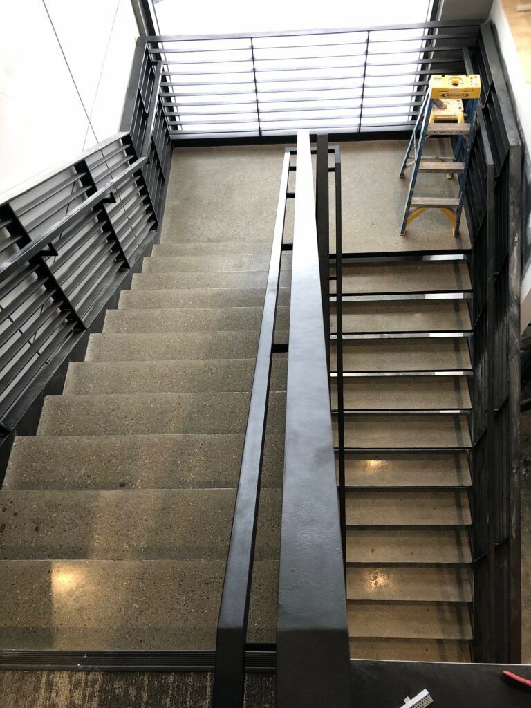 A polished concrete stairway with a large window reflecting light at Lippert Components.